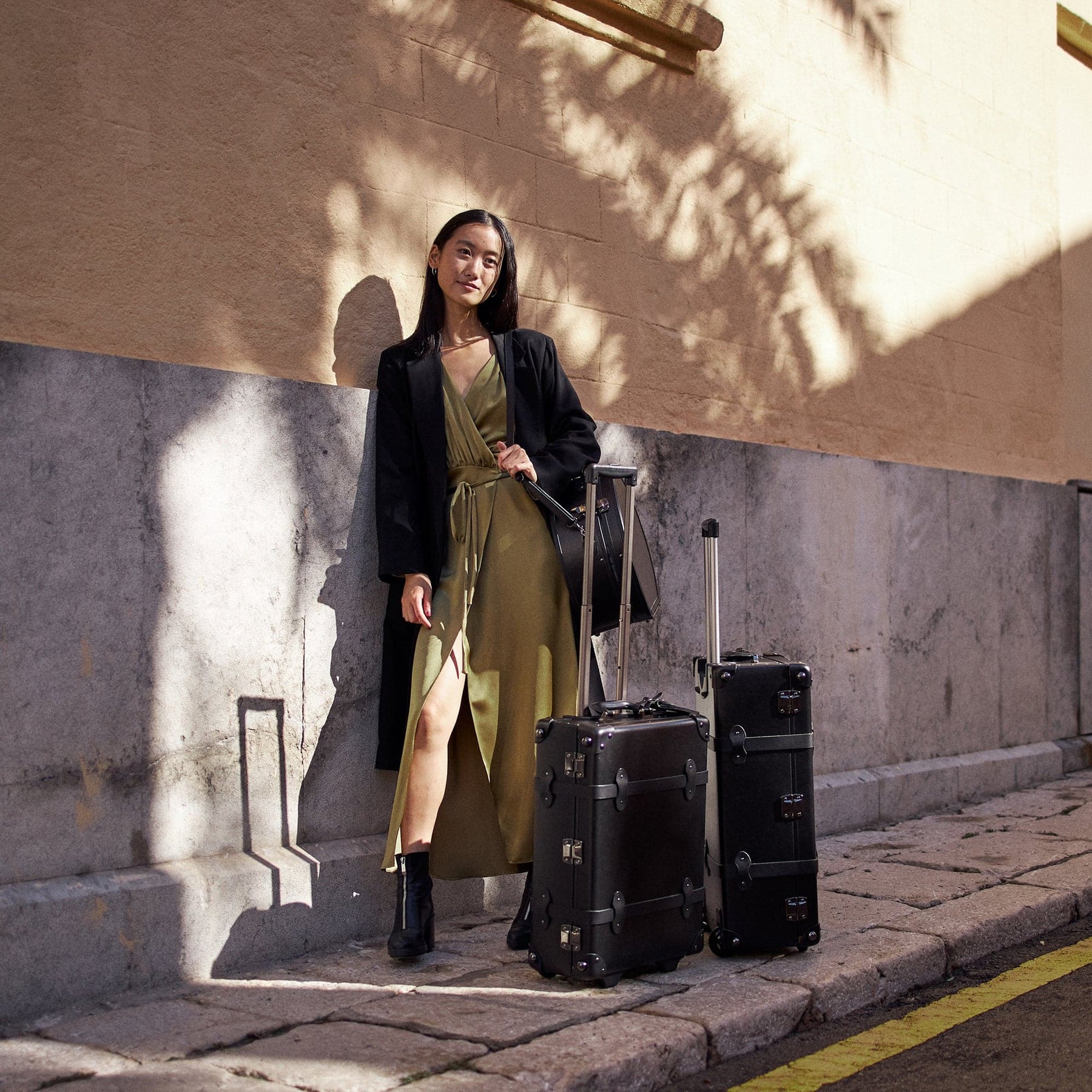 Lifestyle image of model with The Industrialist fibreboard suitcases in  black