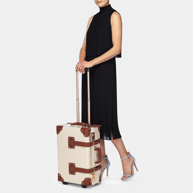 Model with the carry-on Diplomat leather suitcase in cream with raised handle