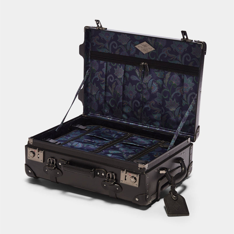 Open product view of the carry-on Industrialist fibreboard suitcase in black with navy paisley print lining and black leather luggage tag