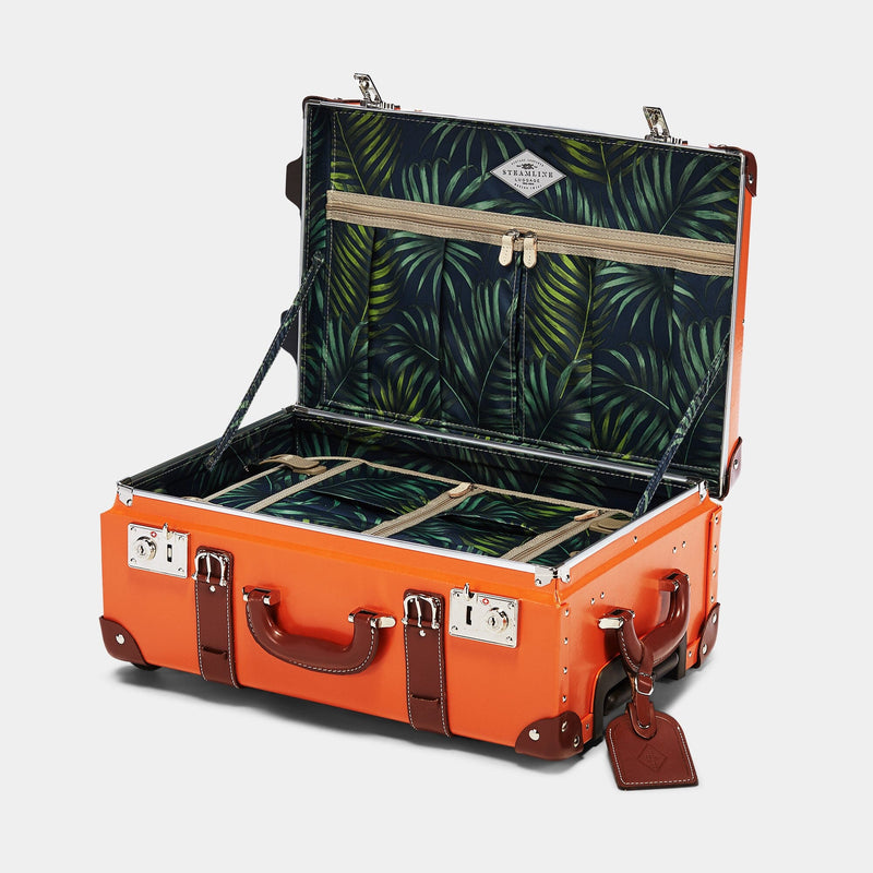 Open product view of the carry-on Anthropologist leather suitcase in orange with green palms print lining and brown leather luggage tag