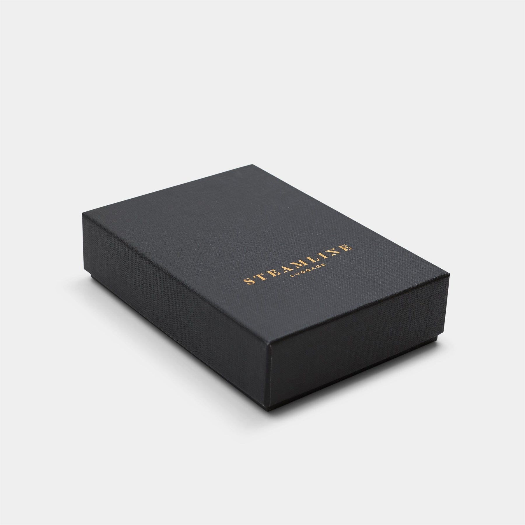 Image of The Navigator passport holder packaging in black with gold Steamline logo