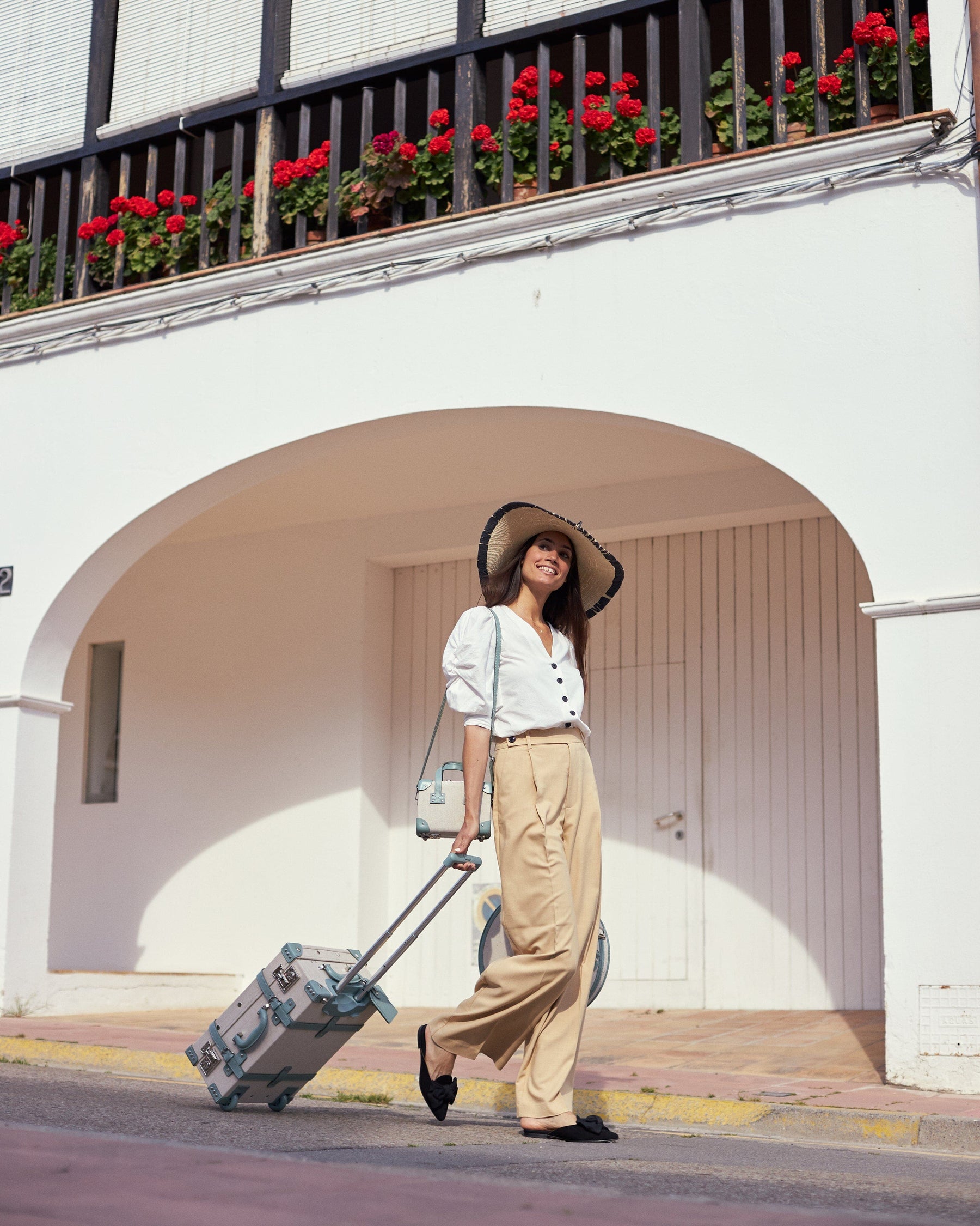 Lifestyle image of model with Editor linen suitcases with sea green trims