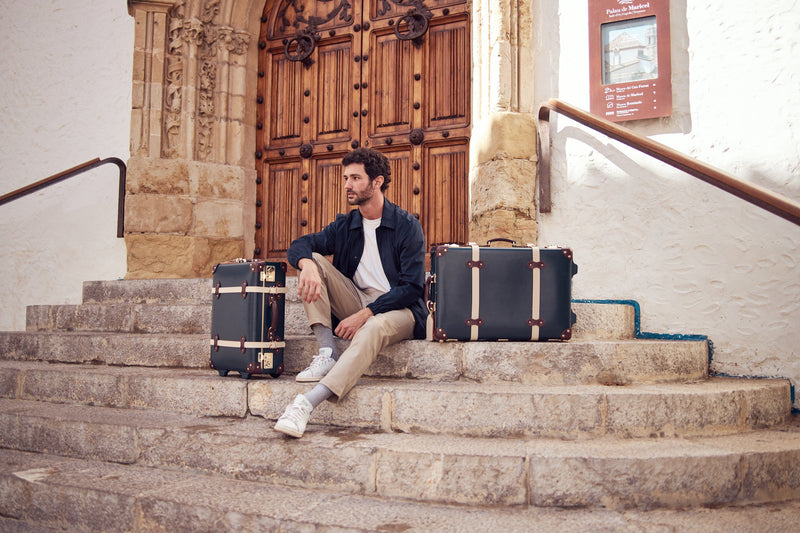 Lifestyle image of model with The Architect leather suitcases in navy