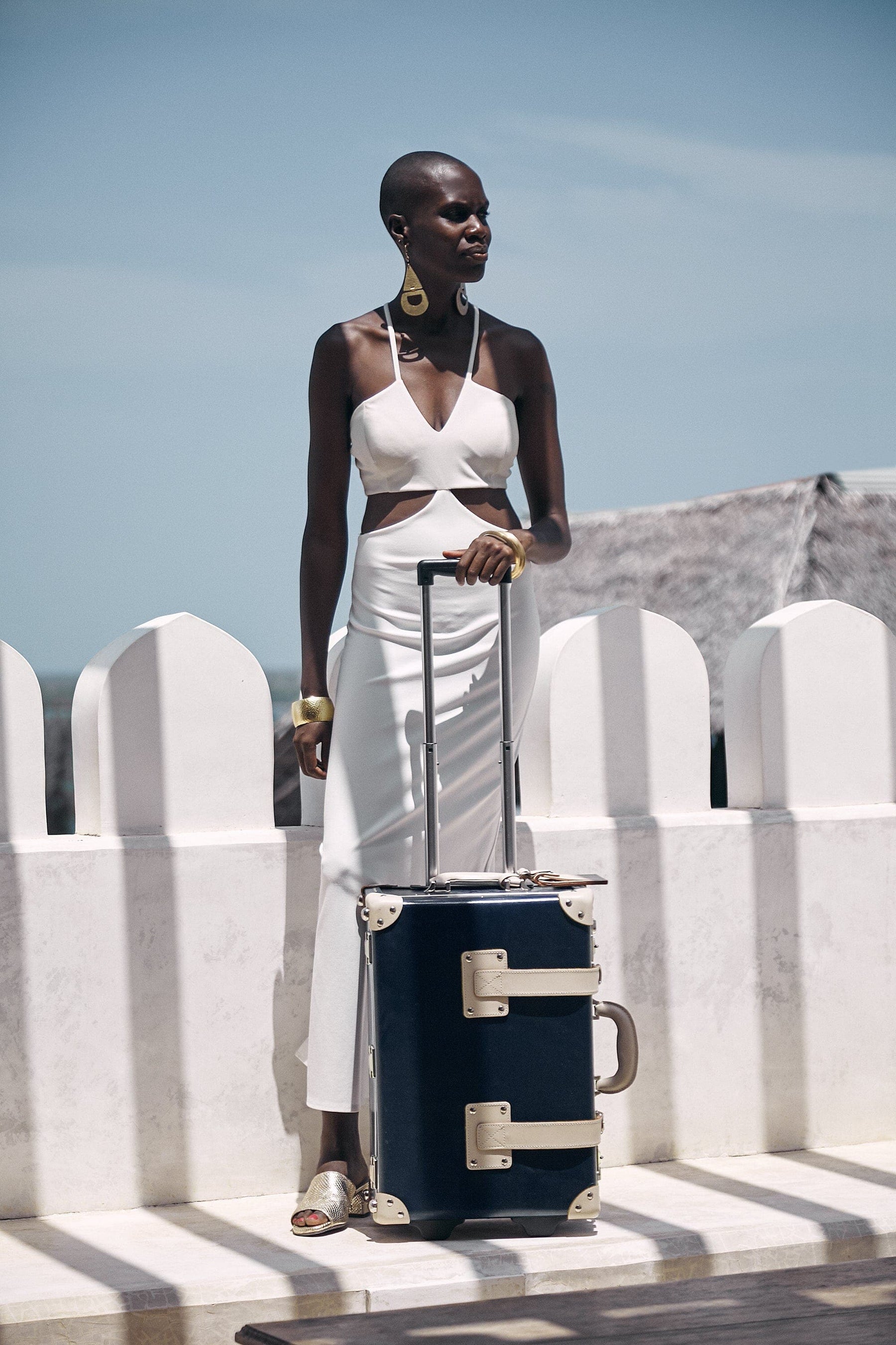 Lifestyle image of model with the carry-on Anthropologist leather suitcase in navy with raised handle