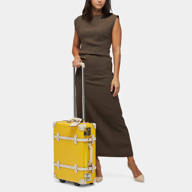 Model with the carry-on Correspondent fibreboard suitcase in canary yellow with raised handle