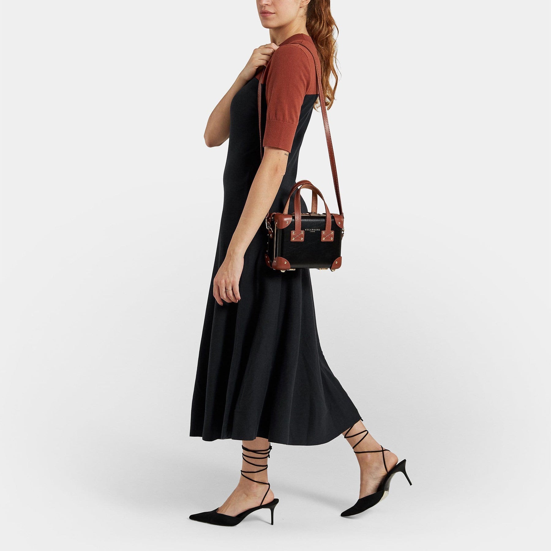 Model with the mini Diplomat leather suitcase in black with shoulder attachment strap