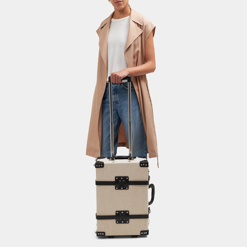 Model with the carry-on Editor linen suitcase with black trims and raised handle