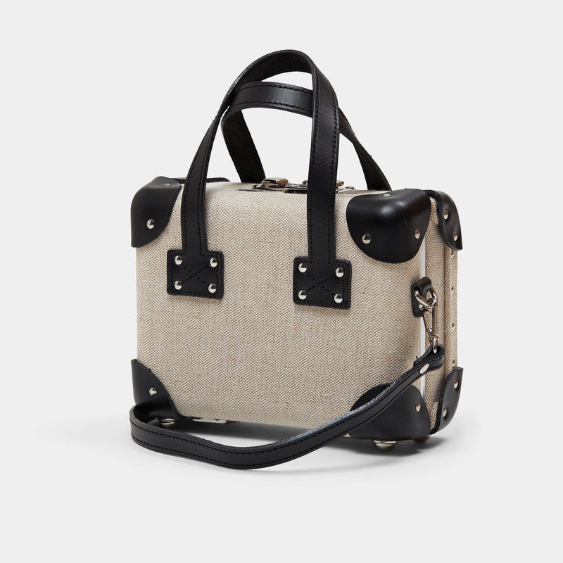 Angled product view of the mini Editor linen suitcase with black trims with shoulder attachment strap