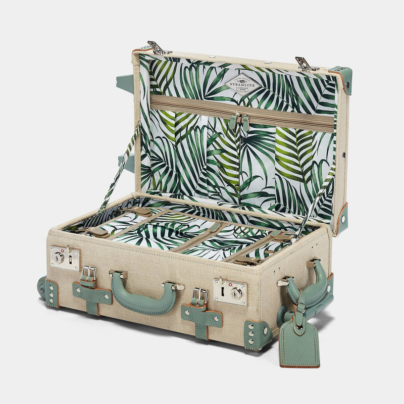 Open product view of the carry-on Editor linen suitcase with sea green trims and palm-leaf print lining and sea green leather luggage tag