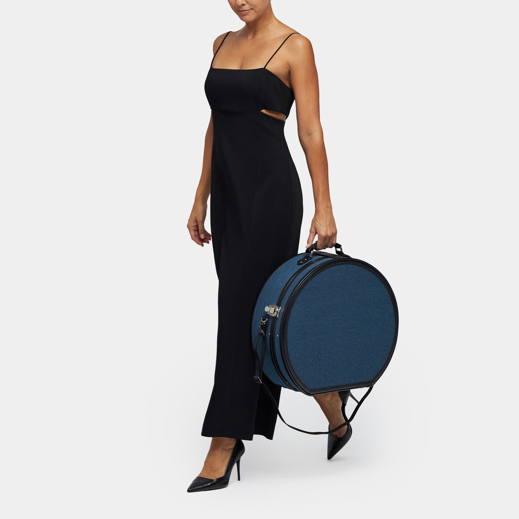 Model  with the deluxe hatbox Editor linen suitcase with navy body, black trims and shoulder attachment strap