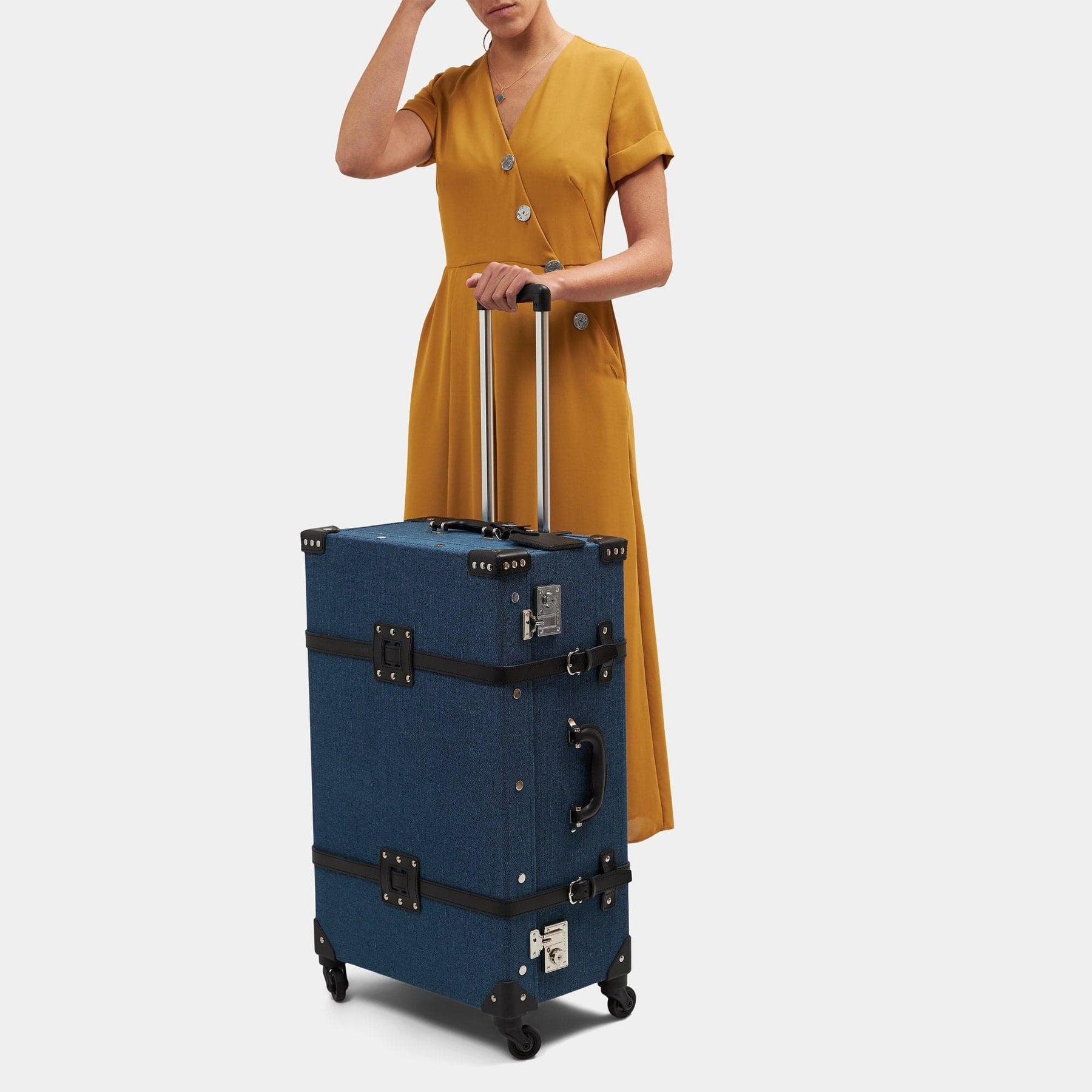 Model with the check-in spinner Editor linen suitcase with navy body, black trims and raised handle