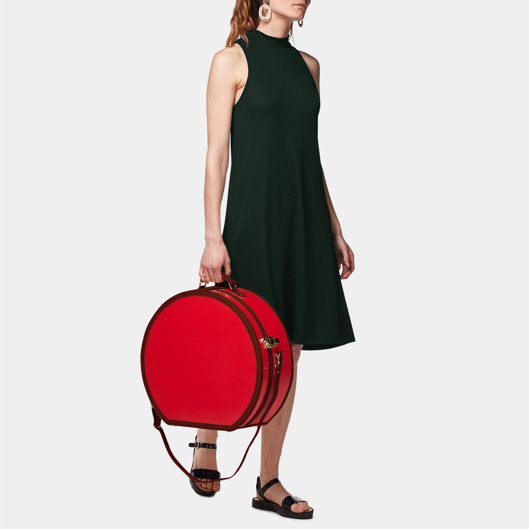 Model  with the deluxe hatbox Entrepreneur vegan leather suitcase in red with shoulder attachment strap