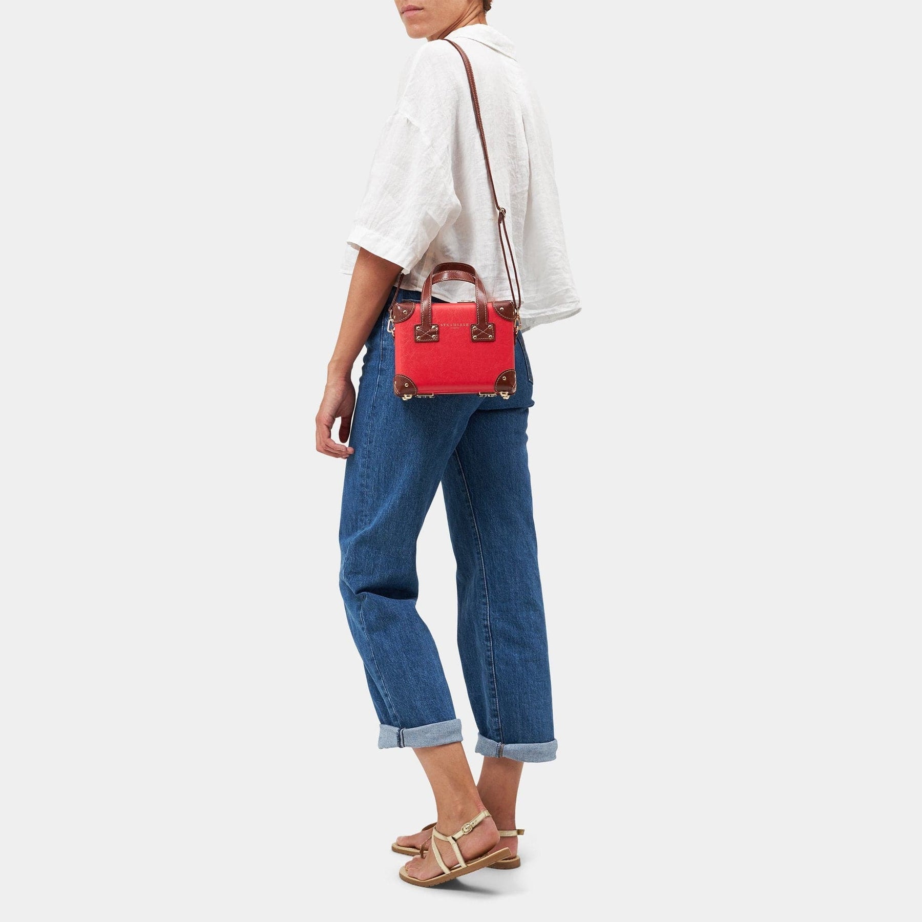 Model with the mini Entrepreneur vegan leather suitcase in red with shoulder attachment strap