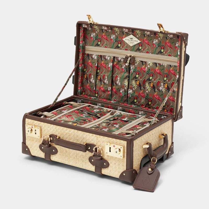 Open product view of the carry-on Explorer rattan suitcase in natural wicker body and brown trims with exotic bird print and brown leather luggage tag