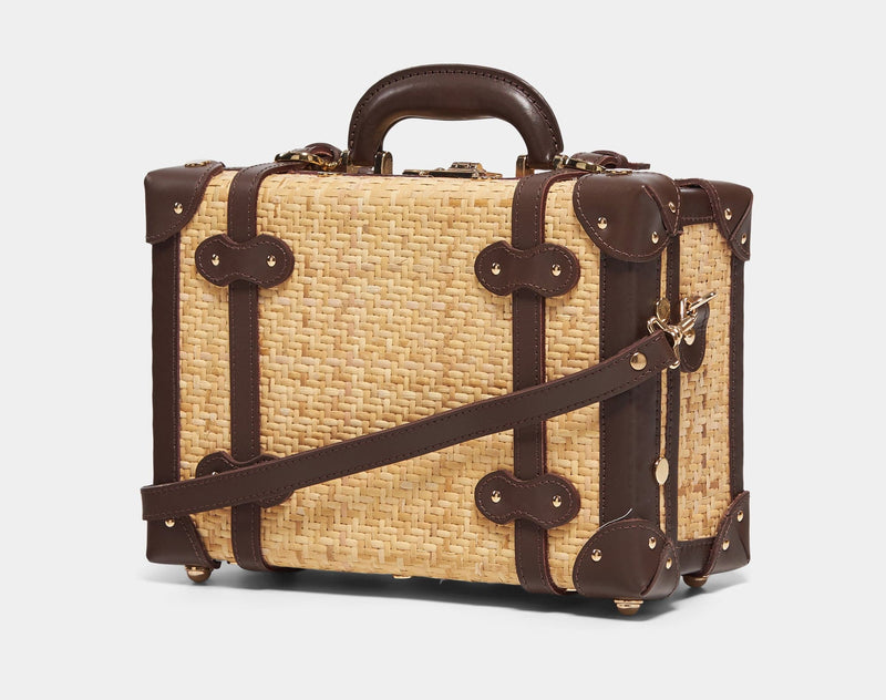 Angled product view of the vanity Explorer rattan suitcase in  natural wicker body and brown trims with shoulder attachment strap