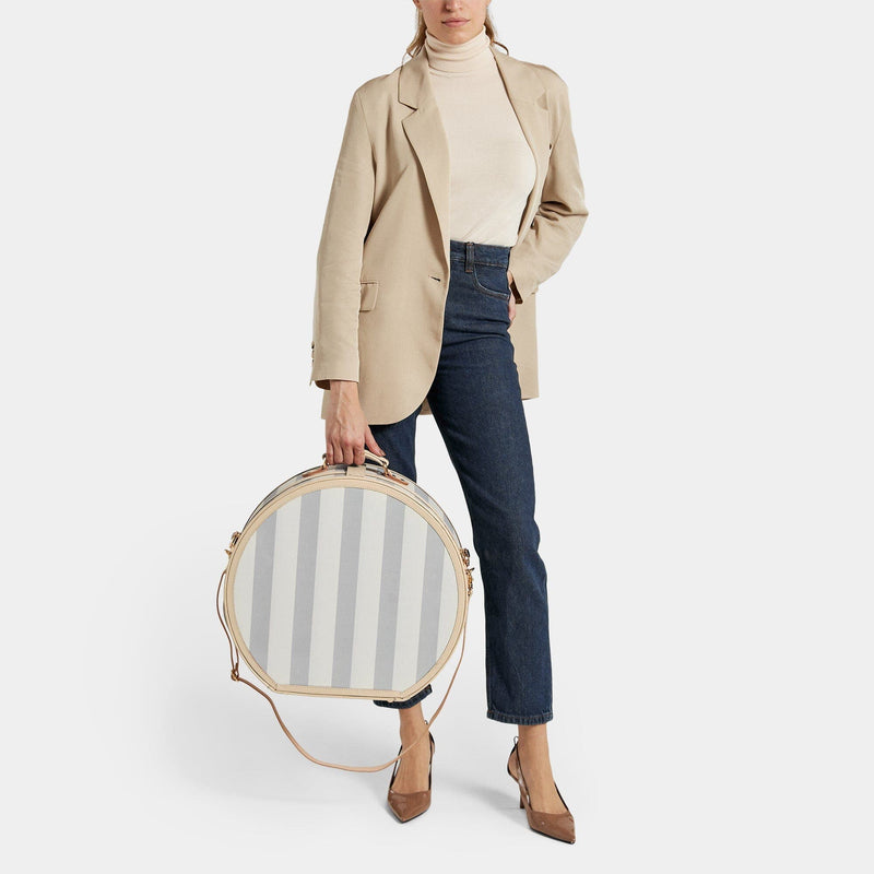 Model  with the deluxe hatbox Illustrator fibreboard suitcase in blue-stripe with shoulder attachment strap