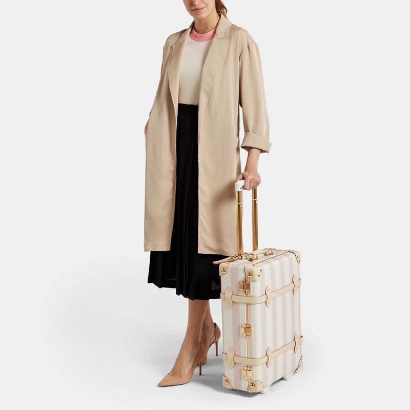 Model with the carry-on Illustrator fibreboard suitcase in pink-stripe with raised handle