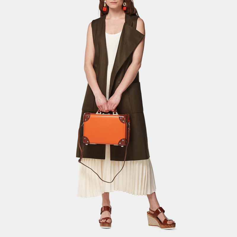 Model with the vanity Anthropologist leather suitcase in orange with shoulder attachment strap