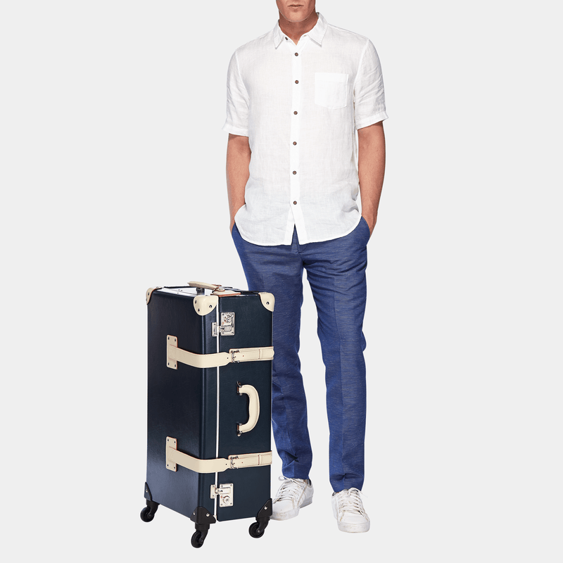 Male model with the check-in Anthropologist leather suitcase in navy with raised handle