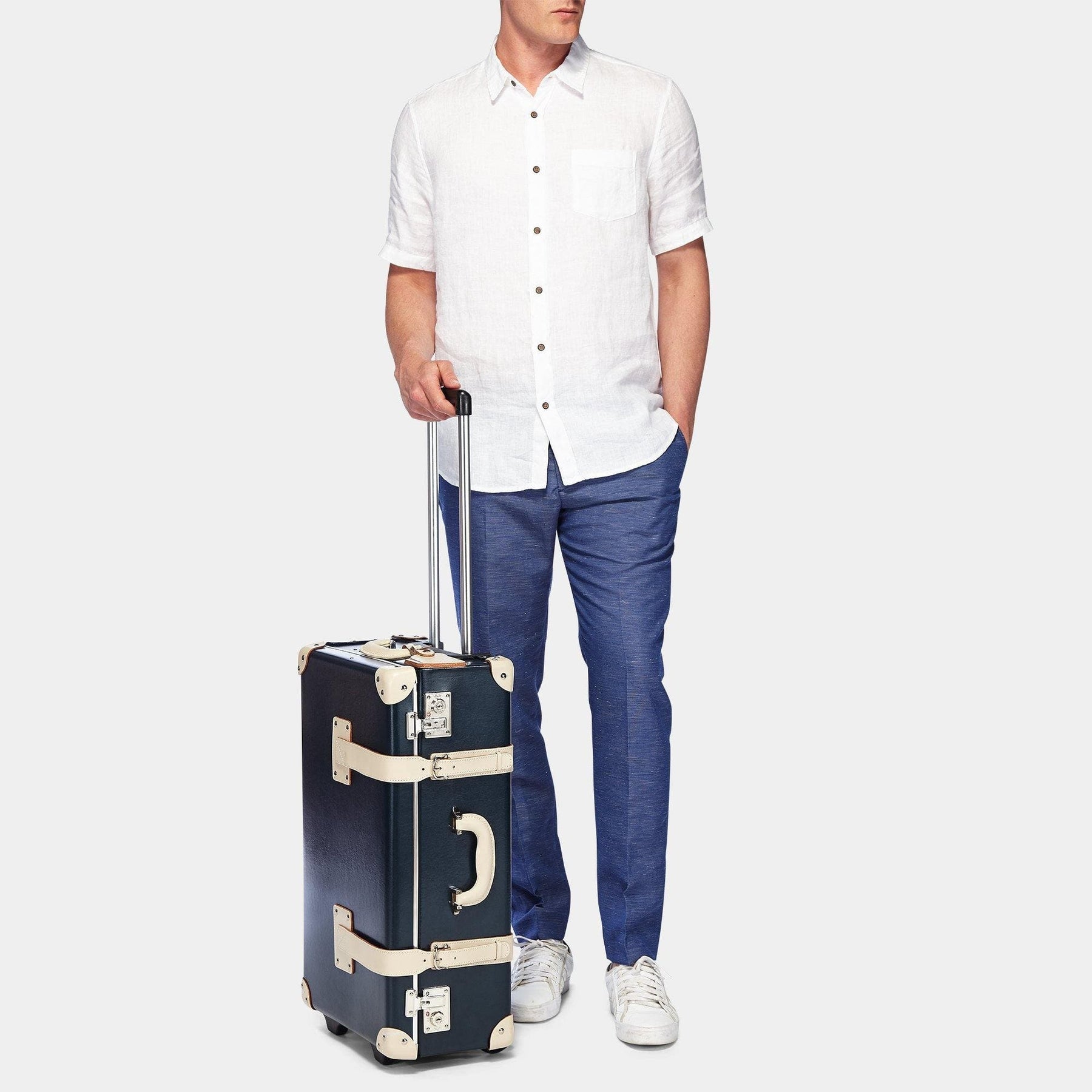 Male model with the stowaway Anthropologist  leather suitcase in navy with raised handle