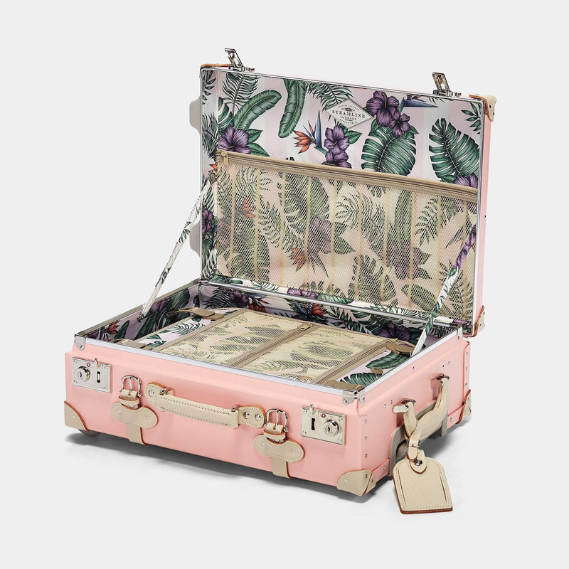 Open product view of the carry-on Botanist fibreboard suitcase in pink with palm & flower printed lining and ivory leather tag
