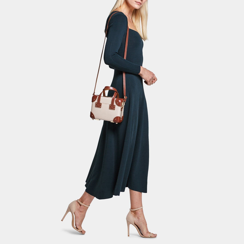 Model with the mini Diplomat leather suitcase in cream with shoulder attachment strap