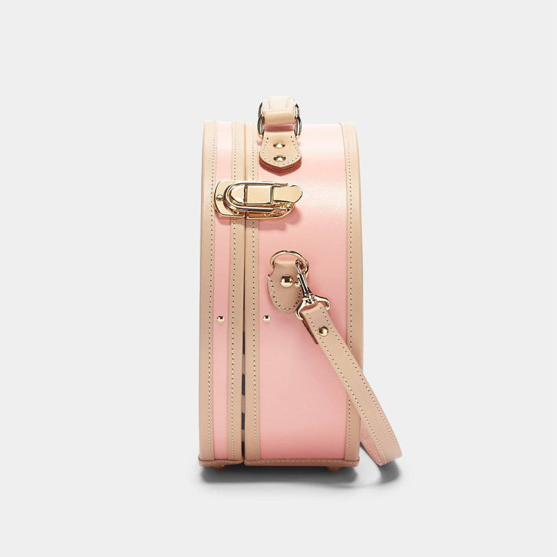 Side product view of the small hatbox Correspondent fibreboard suitcase in pink with shoulder attachment strap